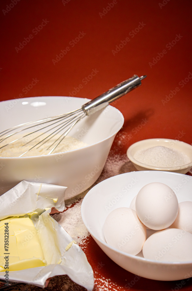 Ingredients for cooking in bowls, photo from the side on a bright red background, preparation for baking Ingredients for cooking in bowls, photo from the side on a bright red background, preparation for baking