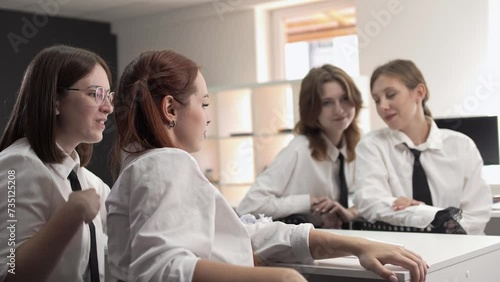 Cute schoolgirls gossip and laugh sitting at their desks during class  photo