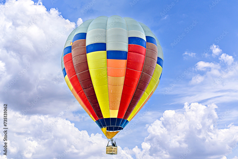 Obraz premium Colorful hot air balloon flying over blue sky with white clouds 