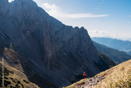 Hiker woman with panoramic view of majestic mountain cliff Schartenspitze in untamed Hochschwab mountain region, Styria, Austria. Scenic hiking trail in remote Austrian Alps. Wanderlust, alpine summer