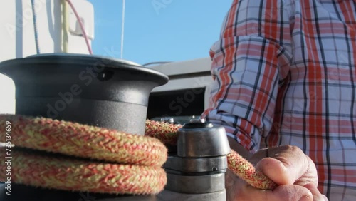 Proficient sailor secures sails by coiling rope around halyard. Captain of sailboat precisely understands how to navigate vessel to correct location