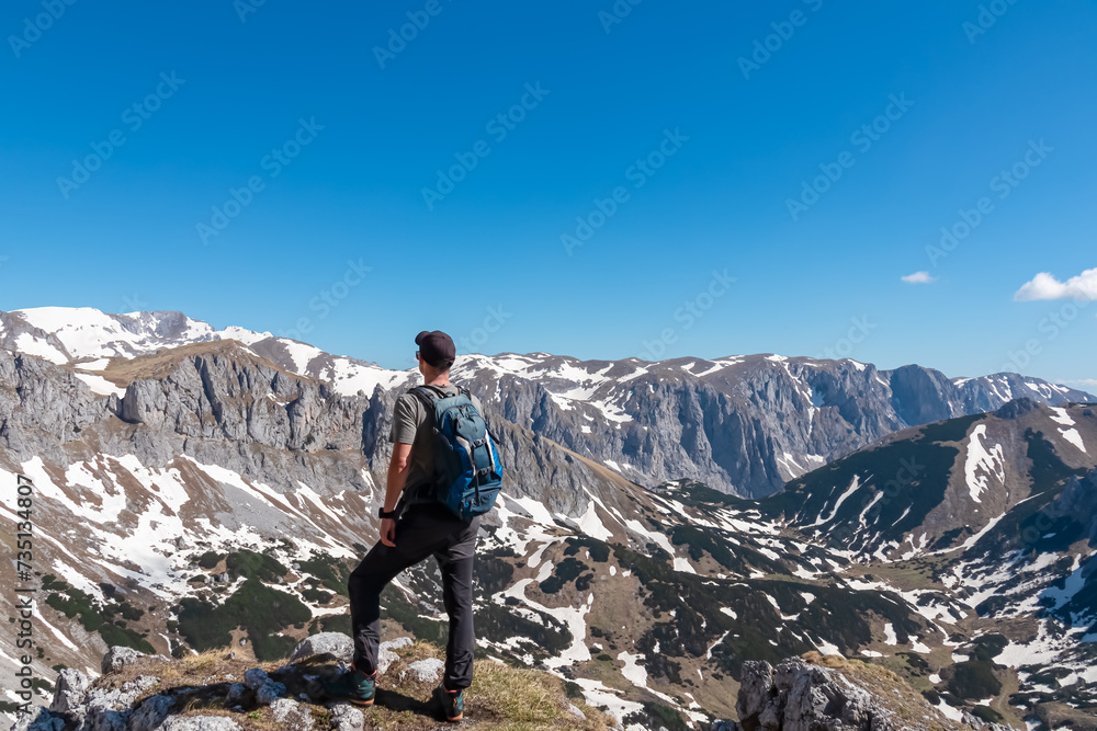 Hiker man with panoramic view of majestic mountain peak Ringkamp in wild Hochschwab massif, Styria, Austria. Scenic hiking trail in remote Austrian Alps on sunny day. Wanderlust in alpine spring