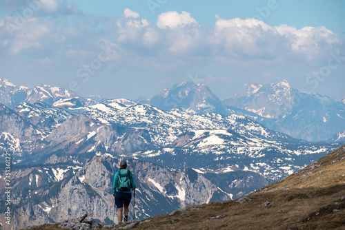 Hiker woman with panoramic view from mountain summit Foelzstein in Hochschwab massif, Styria, Austria. Looking at majestic Ennstaler Alps in Gesaeuse in distance. Wanderlust in remote Austrian Alps