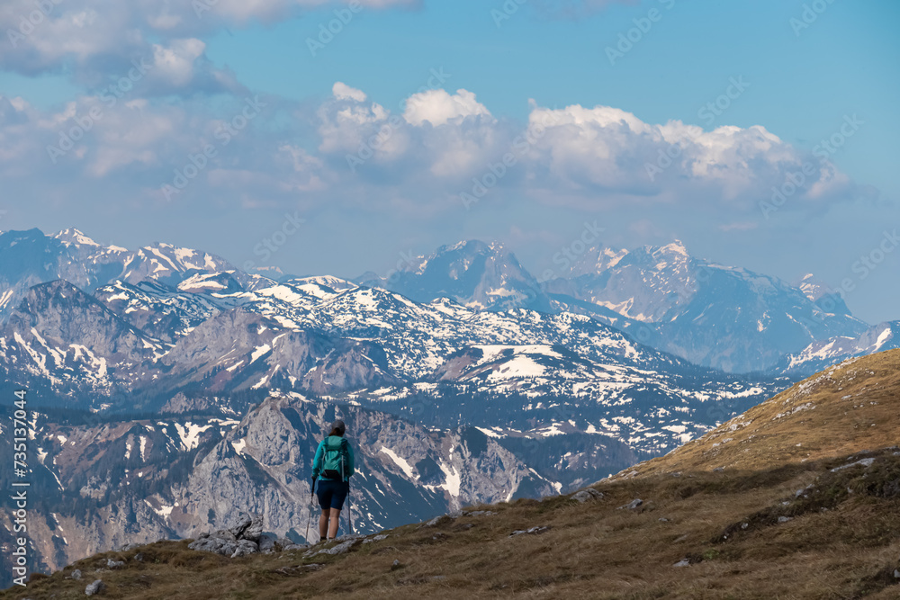 Hiker woman with panoramic view from mountain summit Foelzstein in Hochschwab massif, Styria, Austria. Looking at majestic Ennstaler Alps in Gesaeuse in distance. Wanderlust in remote Austrian Alps