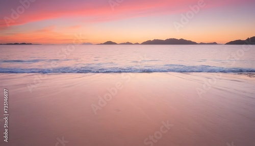 A vertical image of a tide on the beach over the sand during a colorful sunset with the islands