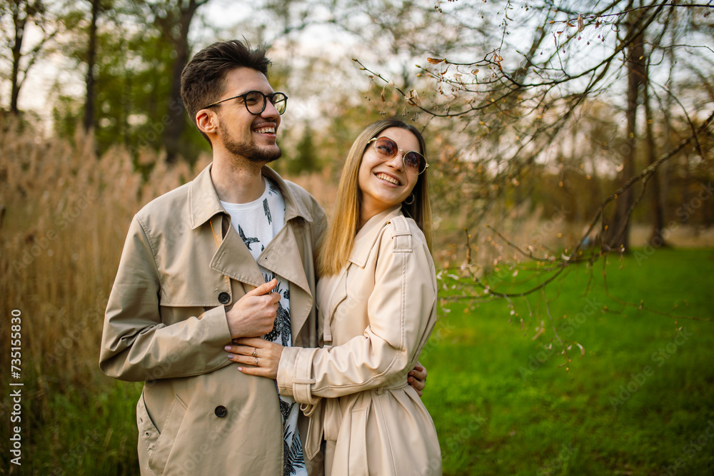 Stylish young couple posing in a spring forest garden. Man and woman smiling with teeth laughing. Relaxation, youth, love, lifestyle solitude with nature.