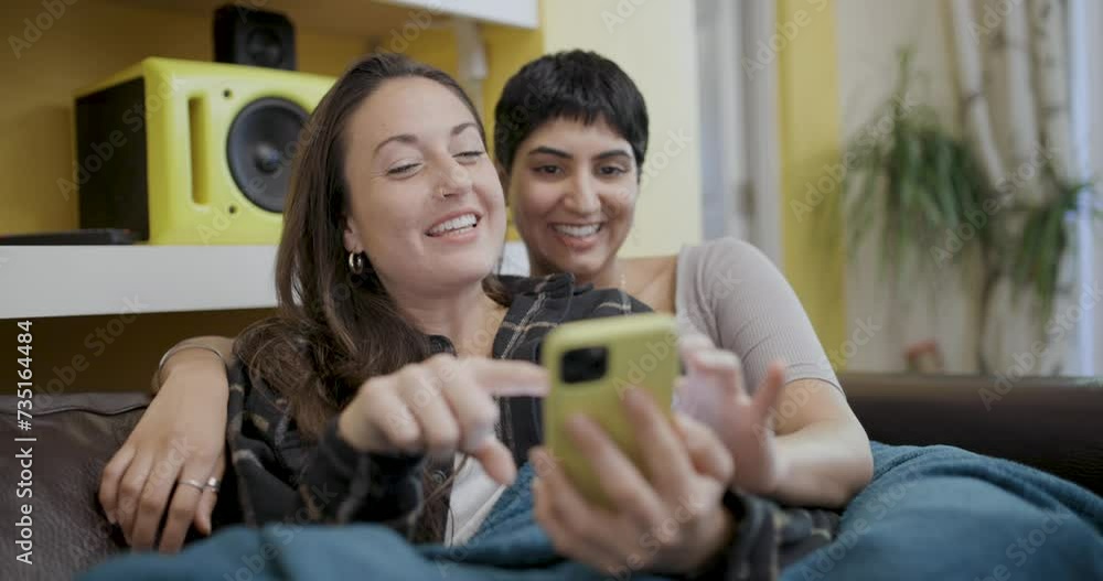 Happy lesbian couple smiling and relaxing on the sofa Happy lesbian couple smiling and relaxing on the sofa