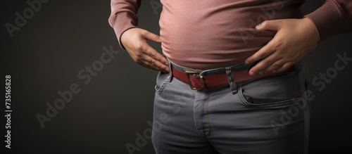 Man looking over his overweight stomach loosening worn out belt. Creative Banner. Copyspace image photo