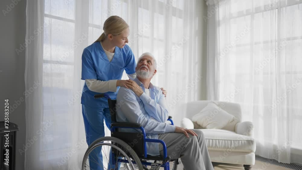 Old man in wheelchair talks with nurse. Senior paralyzed male thanks social worker girl for help support at home. Caregiver holds hand on patient shoulder stands near. Legs paralysis, special needs. Old man in wheelchair talks with nurse. Senior paralyzed male thanks social worker girl for help support at home. Caregiver holds hand on patient shoulder stands near. Legs paralysis, special needs.