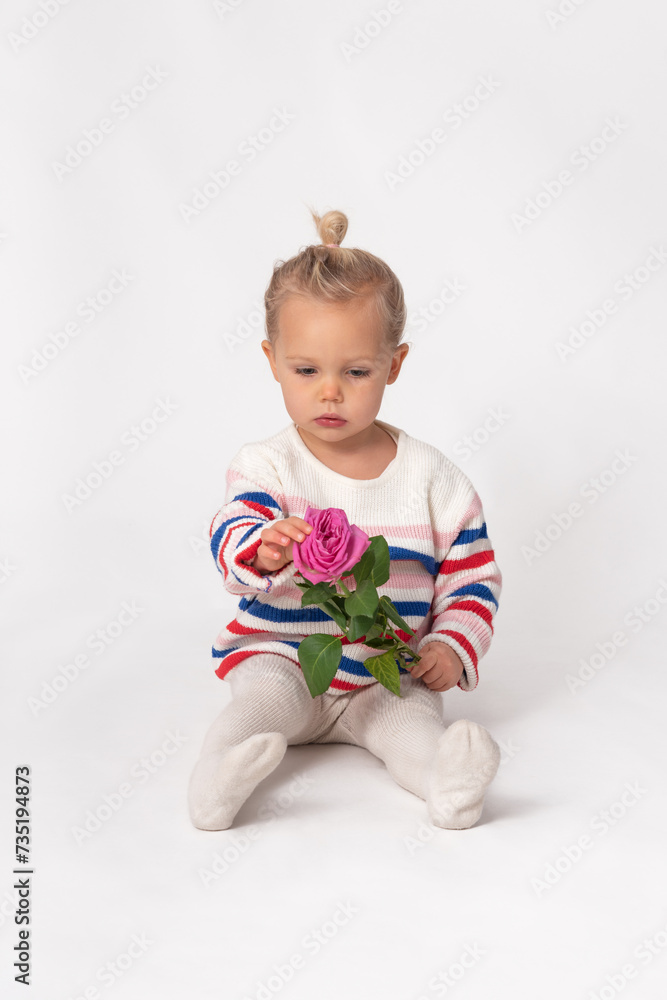 little girl sitting on the ground with a pink rose in her hands little girl sitting on the ground with a pink rose in her hands