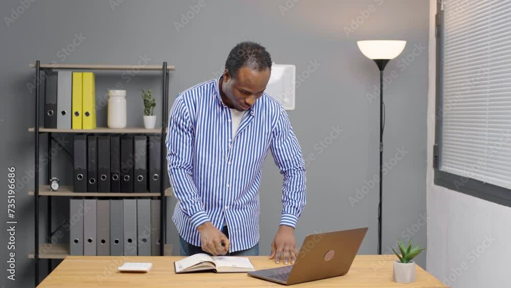 African american man working on laptop looking at camera smiling standing at office. Portrait positive guy in office African american man working on laptop looking at camera smiling standing at office. Portrait positive guy in office