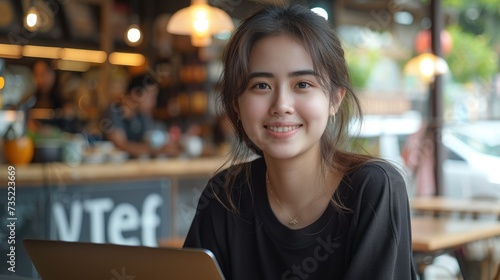 Natural beauty Asian young woman, smiling is write article on her laptop, cafe background