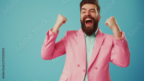 homem barbudo animado de terno rosa mostrando sim gesto isolado em azul photo