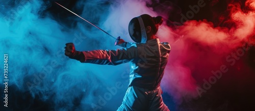 A young woman fencer using a small sword practices fencing isolated on a colorful smoke background photo