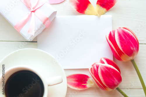 Flat lay photo with coffee cup, gift box and red tulips on wooden background. Beautiful Mother's Day, Women's Day or Valentine greeting card. Mother's Day mockup greeting card