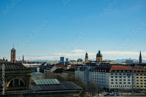 Munich skyline. View from the Technical University Munich, Germany. St. Markus on the left, the domes of the Theatiner Church on the right. In the background the silhouette of the Alps. Blue sky