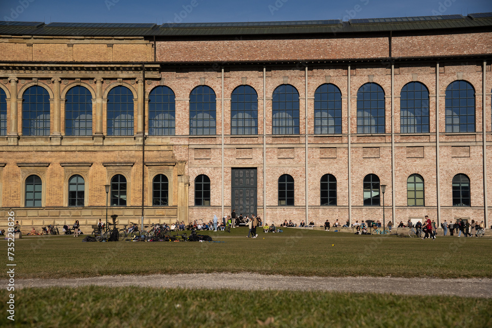 Munich, Germany 02.03.2024. Many people enjoy the spring sunshine at the popular place in front of the Alte Pinakothek in Munich, Germany. Looking through some bare trees