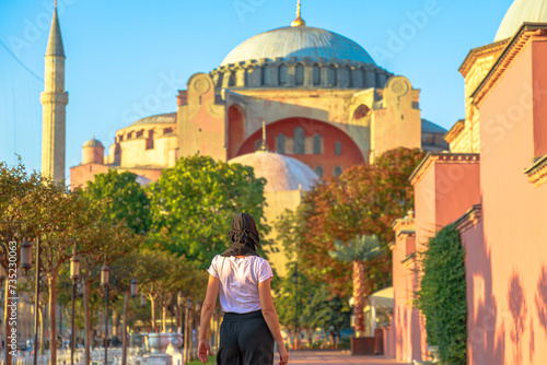 Muslim woman in traditional hijab marvels at amazing panorama of Istanbul's past from Hagia Sophia Grand Mosque. Splendid edifice, erected by Justinian in Turkey, transformed into mosque by Mehmed II. photo