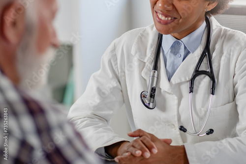 Doctor specialist consulting a patient in a doctor's office at a clinic. Female doctor is talking with a male elderly patient.