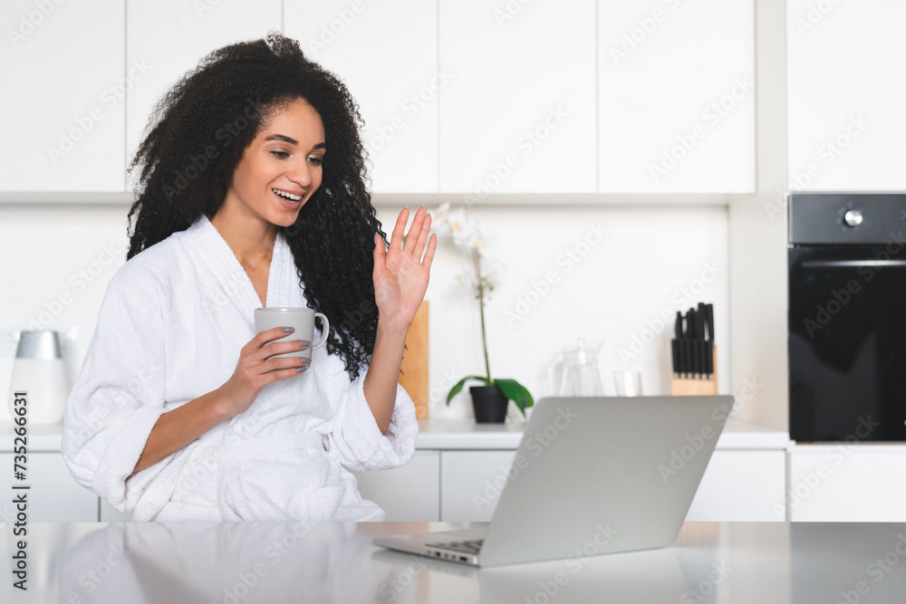 African young woman girl female using laptop for e-learning, having videocall, recording vlog blog online remotely, saying hello in the camera while having breakfast African young woman girl female using laptop for e-learning, having videocall, recording vlog blog online remotely, saying hello in the camera while having breakfast