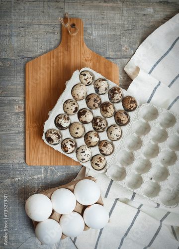 A background with cardboard packaging of different eggs, board and cloth on the table. The concept of healthy natural organic nutrition. Top view. photo