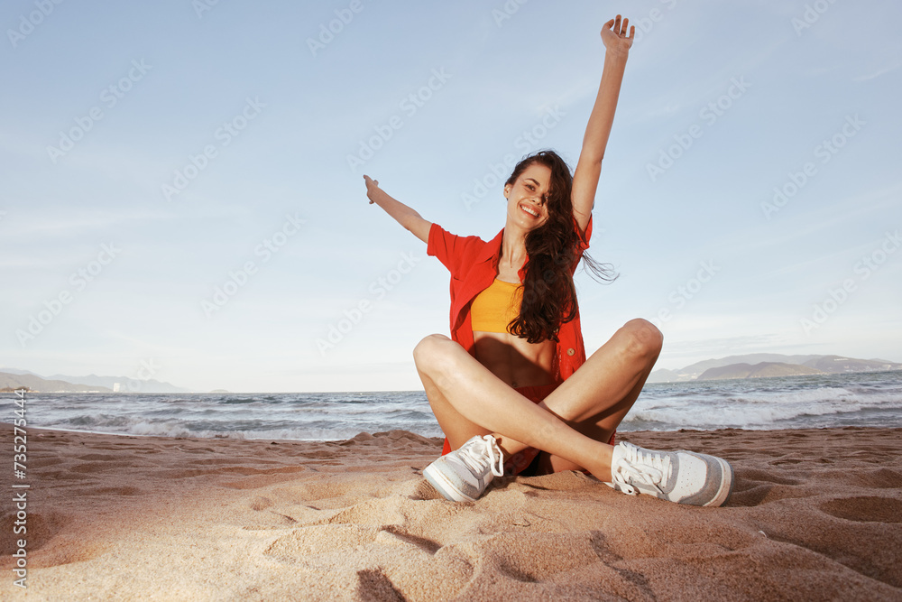 Happy Woman Sitting on Sandy Beach, Enjoying Summer Vacation and Trendy Fashion Outfit under the Wide Angle Sky Happy Woman Sitting on Sandy Beach, Enjoying Summer Vacation and Trendy Fashion Outfit under the Wide Angle Sky