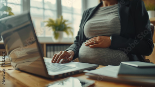 pregnant woman in a professional setting  working on a laptop.