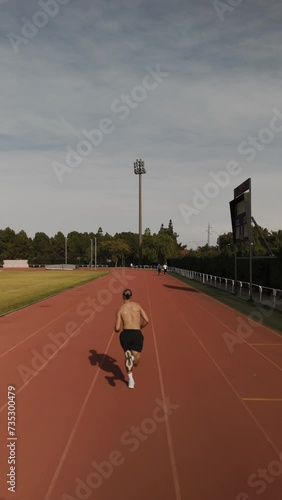 Drone video of an athlete running on the athletics track in the morning. Concept of concentration and effort. Vertical Video