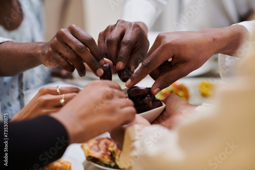 In a poignant close-up  the diverse hands of a Muslim family delicately grasp fresh dates  symbolizing the breaking of the fast during the holy month of Ramadan  capturing a moment of cultural unity