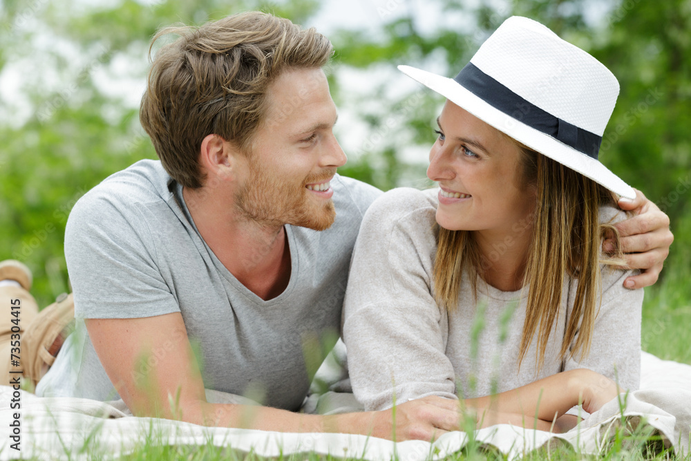 sweet couple embracing while laying on a blanket outdoors