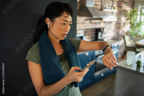Asian woman checking smartwatch after home workout photo