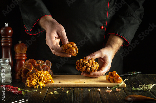 Fresh raw mushrooms in the hands of a chef. Sorting and cleaning mushrooms before cooking in public house kitchen. photo