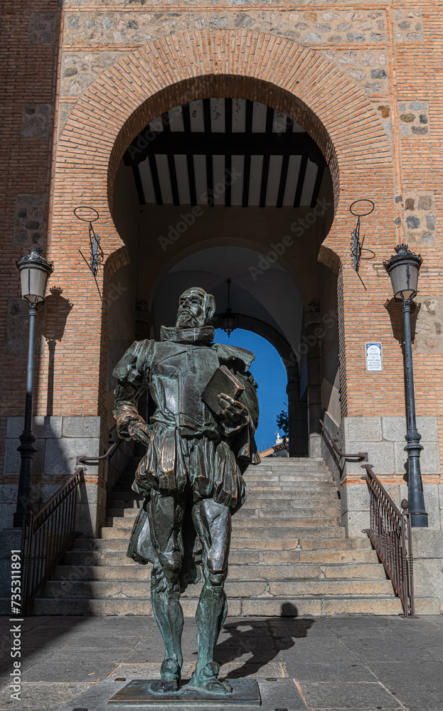 Statue of Cervantes by the Arco de la Sangre, a historic Arab city gate, formerly Bab-al-Yayl in the old Imperial City of Toledo in Castile La Mancha, Spain.