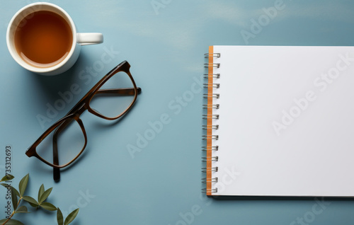 a paper notebook and coffee in a gray background with glasses