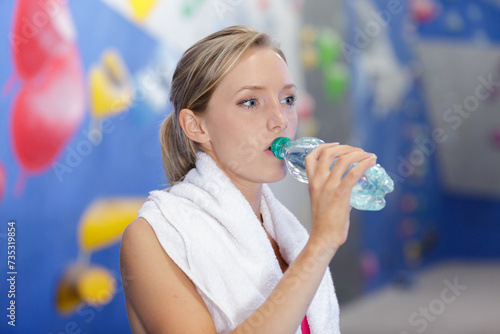 sporty young woman drinking water in gym
