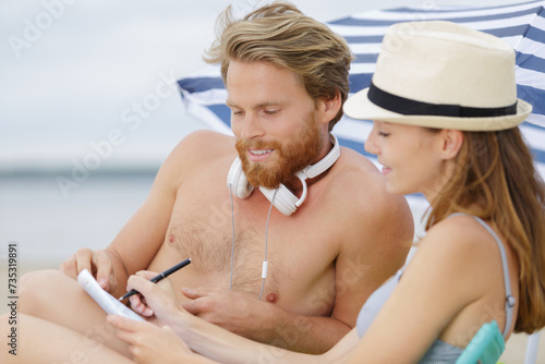 woman and man holding a book on the beach