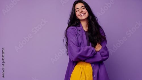 Retrato de uma jovem morena sorridente com jaqueta violeta e calças amarelas sobre fundo roxo photo