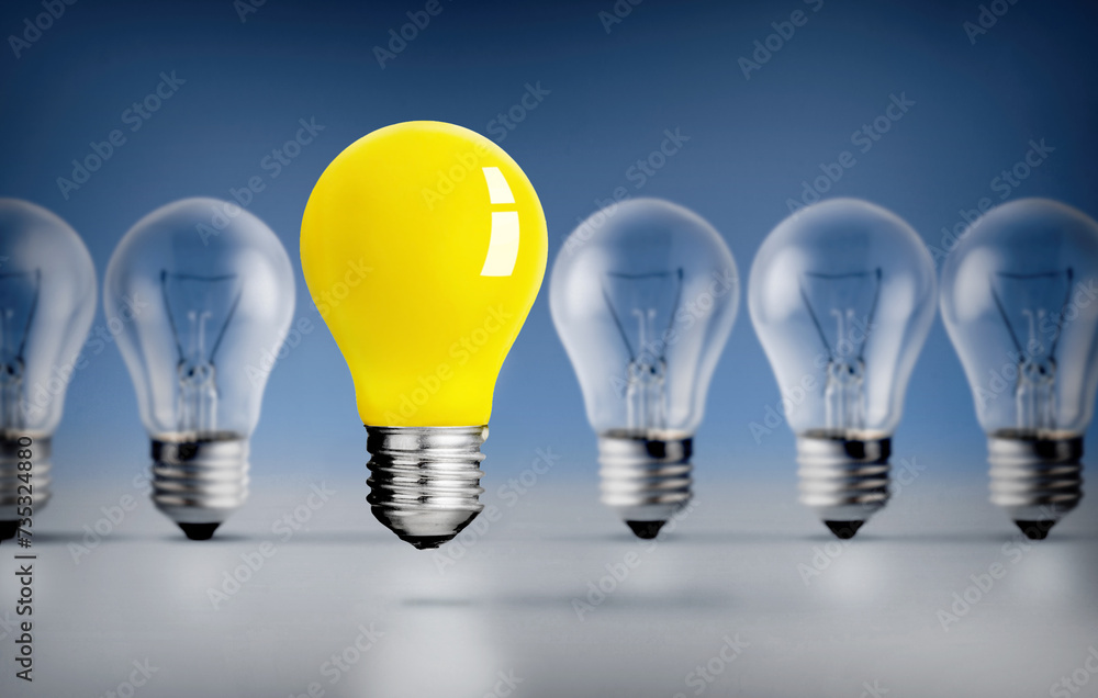 Yellow Light bulb outstanding among lightbulbs on Blue background Yellow Light bulb outstanding among lightbulbs on Blue background