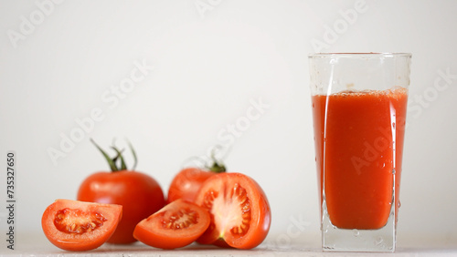 Delicious tomato juice is poured in jug next to tomatoes on the background 