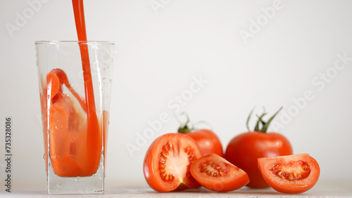 Delicious tomato juice is poured in jug next to tomatoes on the background 