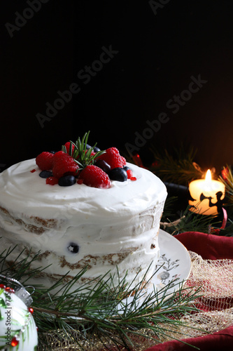 Tradizionale pandoro o panettone natalizio italiano con panna e frutti di bosco su sfondo scuro con decorazioni natalizie. Concetto di tradizioni di Natale e Capodanno.