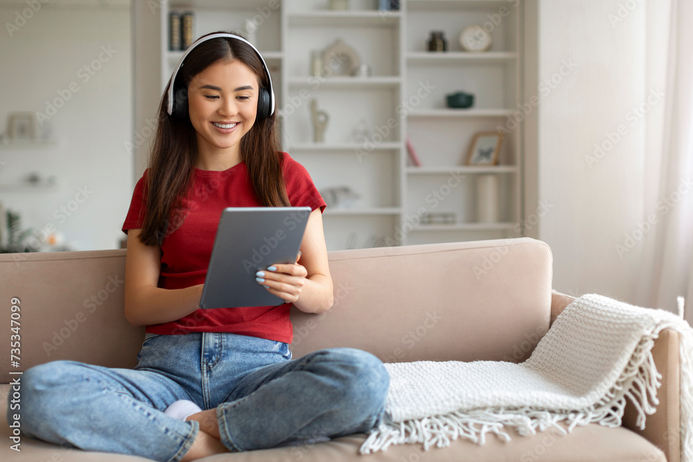 Smiling asian woman wearing headphones using digital tablet at home, Smiling asian woman wearing headphones using digital tablet at home,