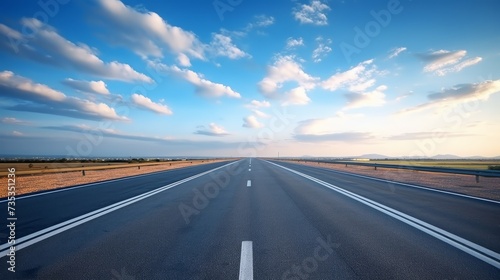 Asphalt road in the field with blue sky and white clouds