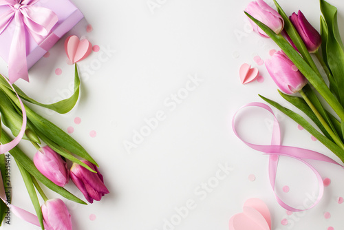 Pink whispers: a march 8th celebration. Top view shot of elegant pink tulips and a beautifully wrapped present on a white background with space for messages celebrating