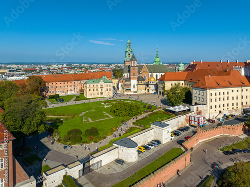 Royal Wawel Gothic Cathedral in Krakow, Poland, with Renaissance Sigismund Chapel with golden dome, walking people and lawn with foundations of an old destroyed building and two churches. Aerial view