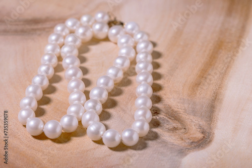 beautiful women's necklace made of natural white sea pearls on a wooden backing