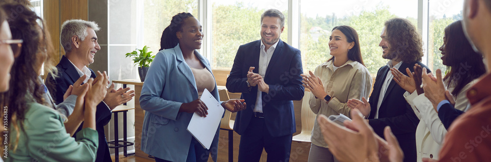Group of happy diverse business people applauding to female speaker standing in a circle in meeting room. Successful company employees clapping a colleague on business training or conference. Banner. - obrazy, fototapety, plakaty 