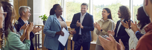 Group of happy diverse business people applauding to female speaker standing in a circle in meeting room. Successful company employees clapping a colleague on business training or conference. Banner.