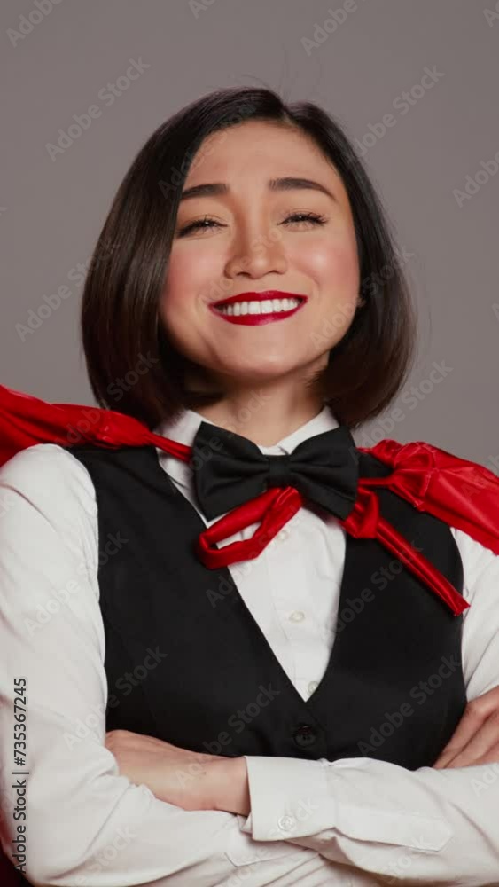 Vertical Video Asian receptionist posing with red superhero cape on camera, feeling confident and powerful while she wears a cloak as a hero. Hotel concierge operator standing with arms crossed Vertical Video Asian receptionist posing with red superhero cape on camera, feeling confident and powerful while she wears a cloak as a hero. Hotel concierge operator standing with arms crossed