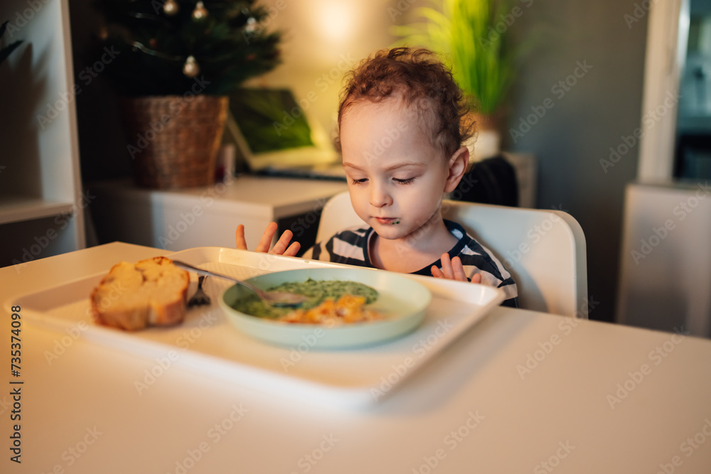 A cute little boy eating his lunch at home.